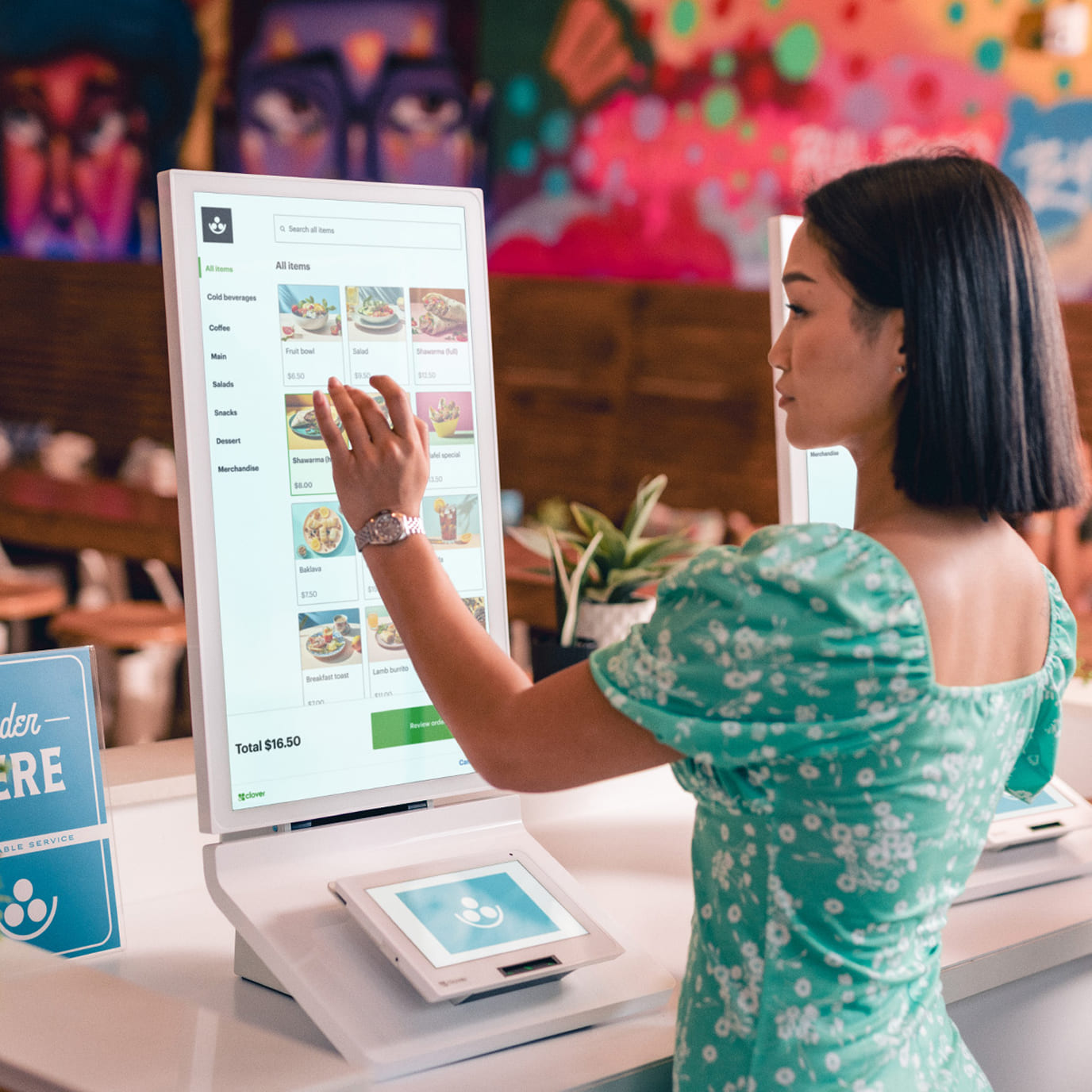 A customer browsing a menu and ordering on a self-service kiosk in a restaurant